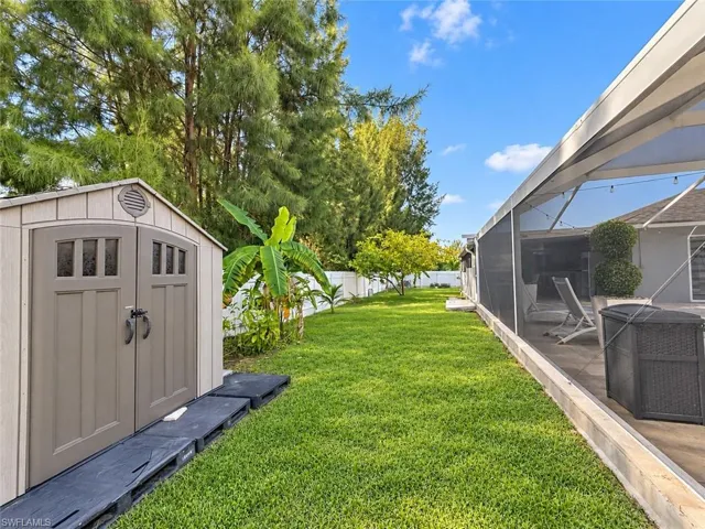 Expansive backyard oasis featuring manicured lawn, mature landscaping with mixed evergreen and deciduous trees, and a banana plant accent