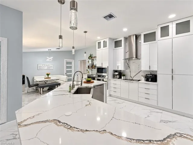Kitchen featuring a large island with a substantial countertop, integrated sink, and pendant lighting