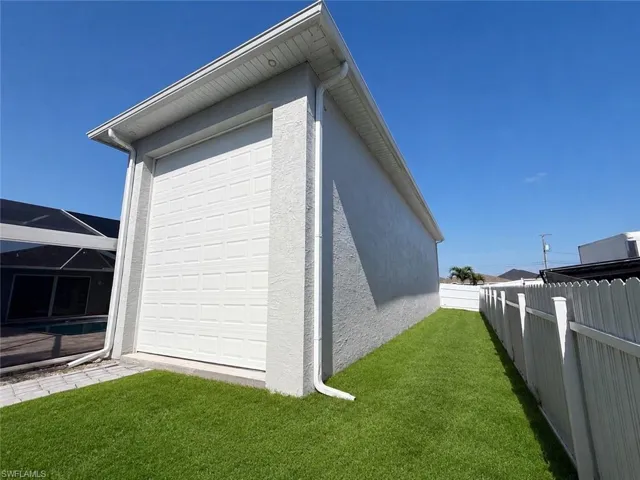 Exterior garage with a paneled door, stucco finish, and integrated gutters