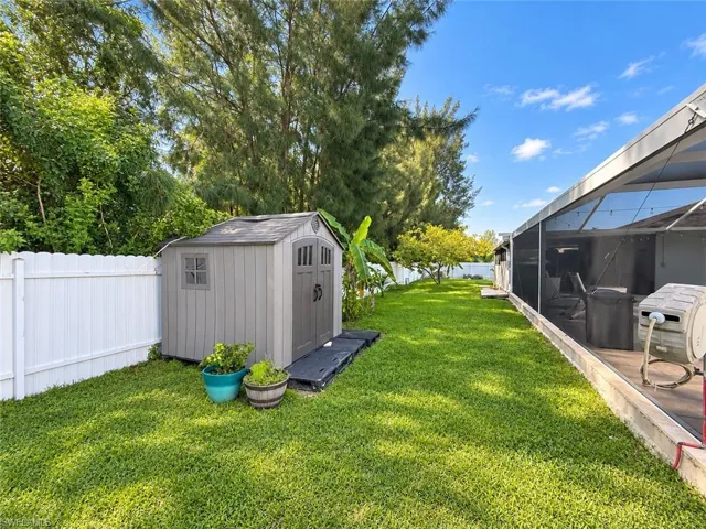 Expansive green lawn with a white privacy fence and a storage shed