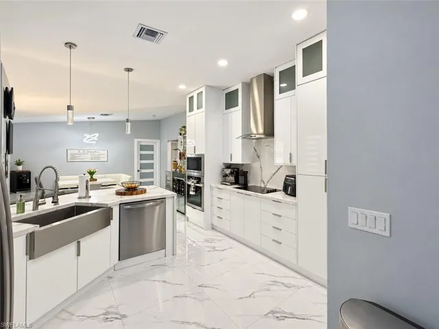 White shaker-style cabinetry, stainless steel appliances, polished tile flooring, and pendant lighting