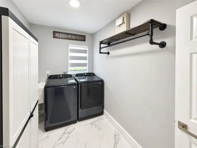 White shaker-style cabinetry, industrial pipe shelving, and marble-finish flooring