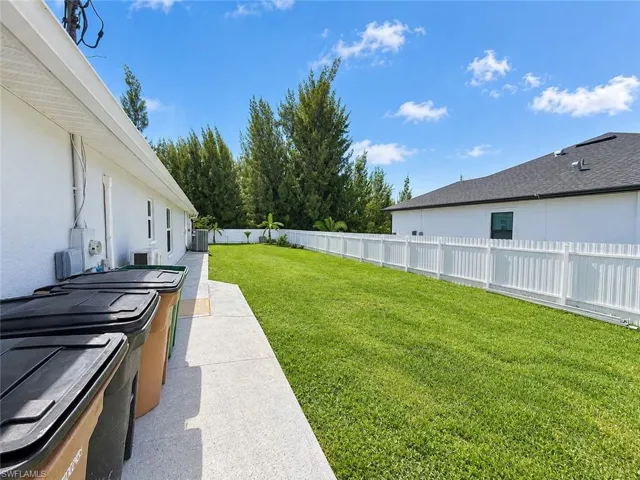 Expansive grassy yard with a white privacy fence
