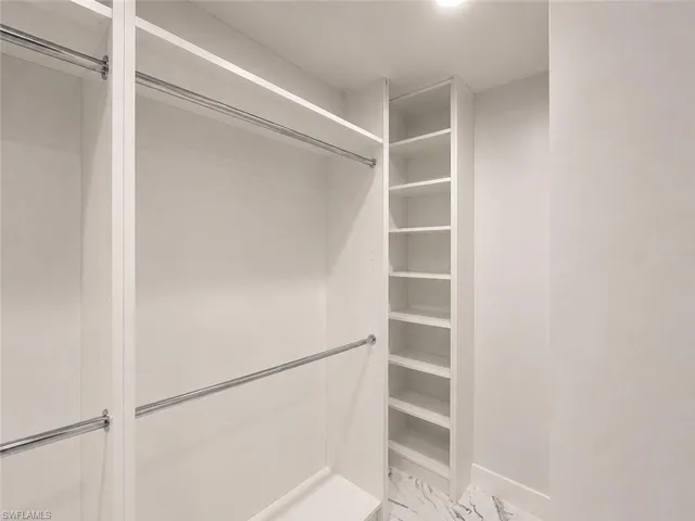Custom closet system featuring built-in shelving, chrome hanging rods, and a white finish
