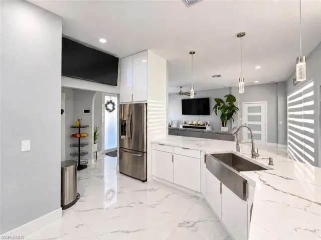 Modern kitchen featuring white cabinetry, a stainless steel refrigerator, and a farmhouse-style sink