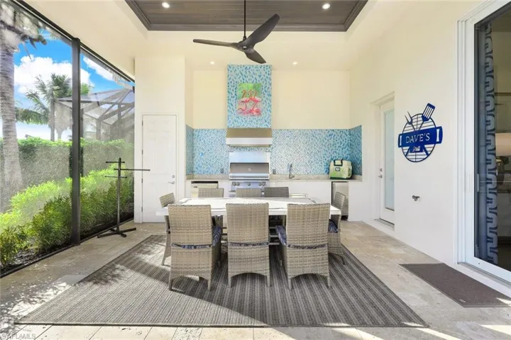Outdoor summer kitchen with Alfresco Gas grill, Ice Maker, Beverage refrigerator, sink wood ceiling detail, recessed lights and access to pool bath and storage closet!