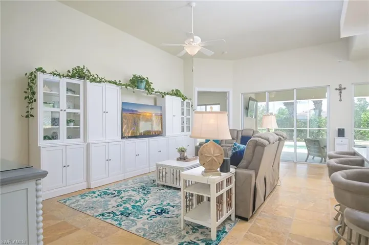 Living room featuring a towering ceiling, light tile flooring, and ceiling fan
