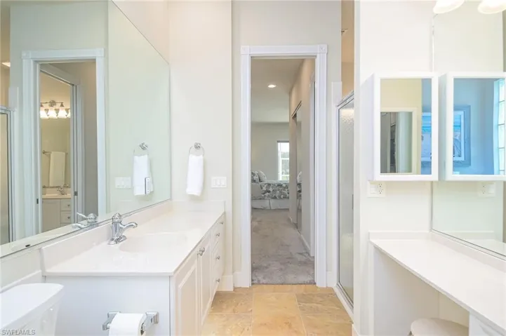 Bathroom featuring vanity, toilet, tile floors, and a shower with door