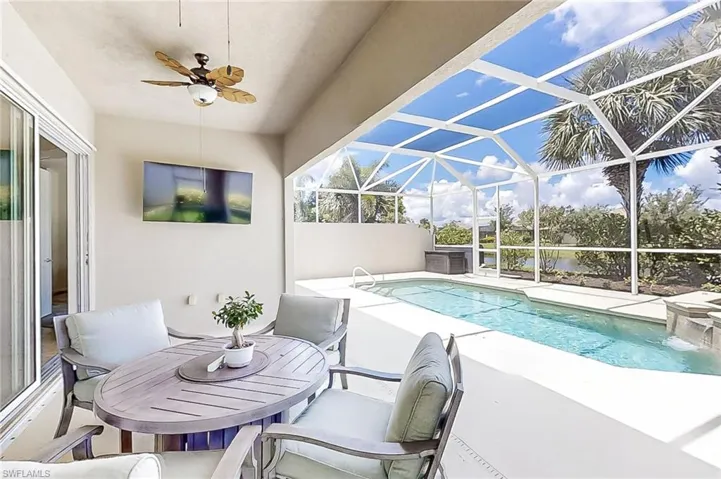 View of pool featuring screened enclosure, pool water feature, a patio area, and ceiling fan