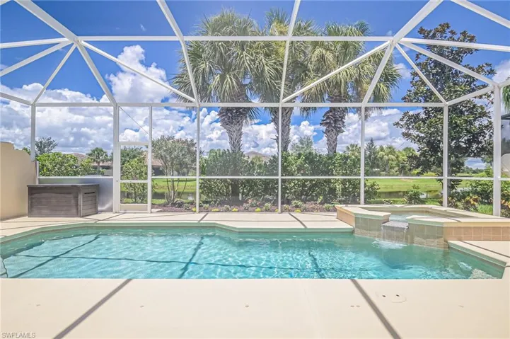 View of swimming pool with pool water feature, glass enclosure, and an in ground hot tub