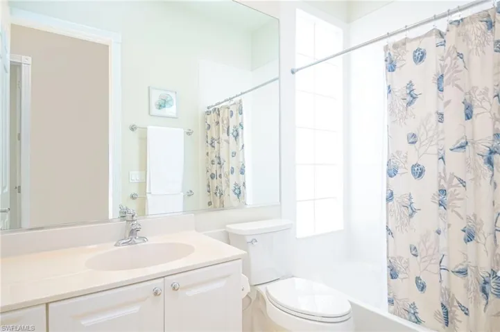 Full bathroom with oversized vanity, toilet, and shower / bath combination with curtain