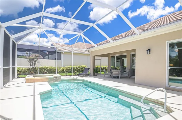 View of swimming pool featuring screened enclosure, an in ground hot tub, and a patio area