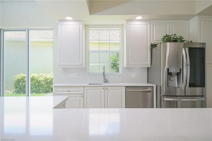 Kitchen featuring appliances with stainless steel finishes, white cabinetry, sink, and light stone counters