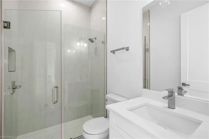 Bathroom with a shower with shower door, vanity, and toilet