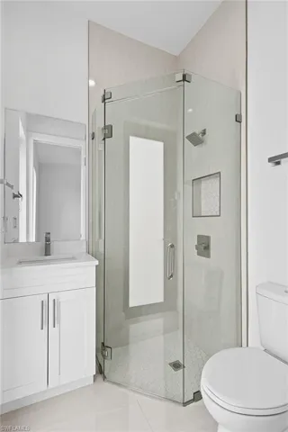 Bathroom featuring vanity, toilet, tile floors, and a shower with door