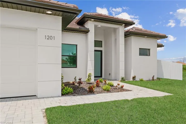 View of exterior entry with a garage and a yard