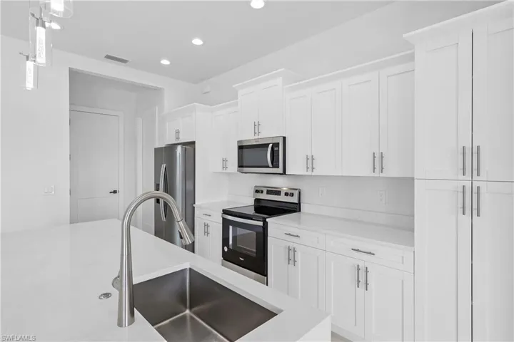 Kitchen featuring white cabinetry, sink, pendant lighting, and stainless steel appliances