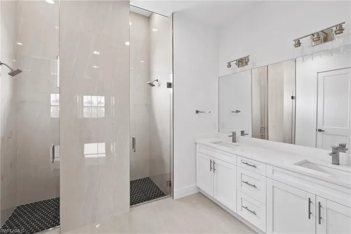 Bathroom featuring a shower with shower door, dual vanity, and tile flooring