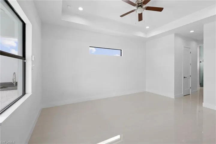 Unfurnished room with sink, a wealth of natural light, ceiling fan, and a raised ceiling