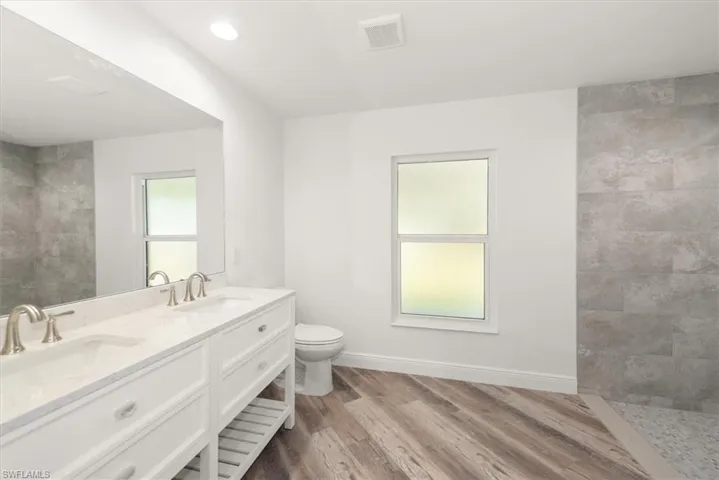 Primary bathroom has dual sinks with quartz countertops, soft close drawers, and a walk in shower with 12 x 24 plank pocelain tile.