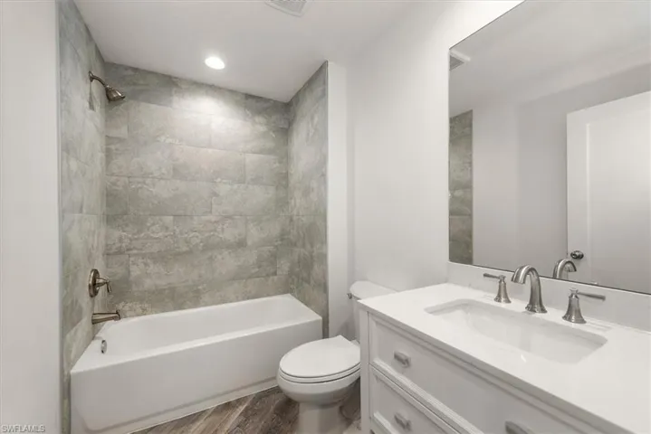 Guest bathroom with 12 x 24 plank porcelain tile to the ceiling. Bathroom vanity has quartz countertops with soft close drawers.