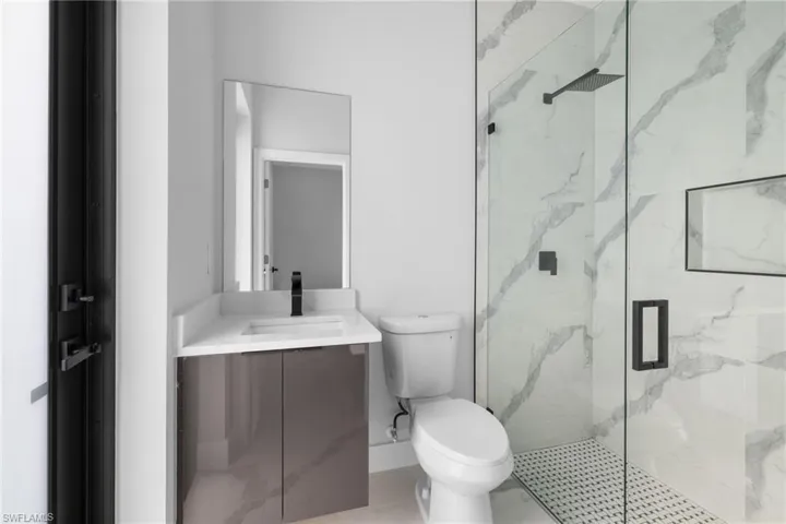 Bathroom featuring tile patterned floors, toilet, vanity, and walk in shower