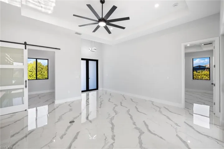 Spare room with a barn door, a tray ceiling, and ceiling fan