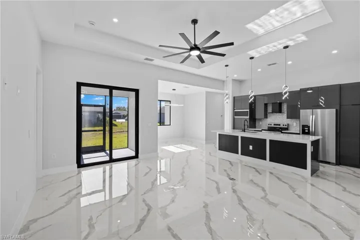 Kitchen with tasteful backsplash, stainless steel appliances, a kitchen island with sink, ceiling fan, and decorative light fixtures