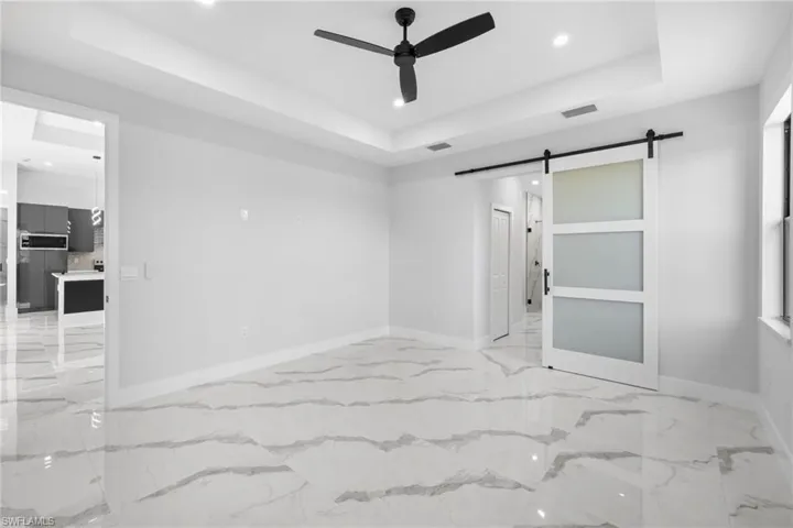 Spare room featuring ceiling fan, a barn door, and a raised ceiling
