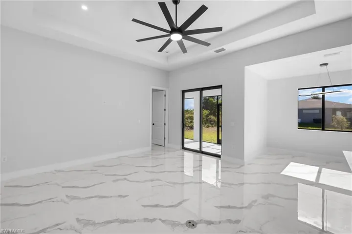 Unfurnished room with plenty of natural light, ceiling fan, and a raised ceiling