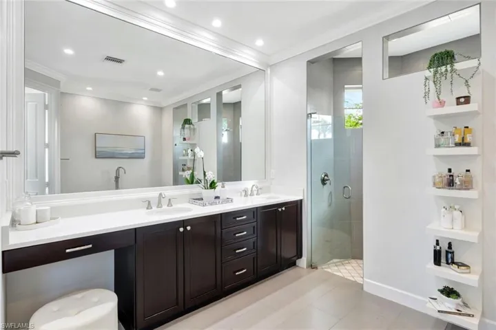 Bathroom with vanity, a shower with shower door, and ornamental molding