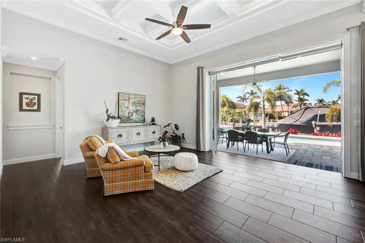 Living area featuring coffered ceiling, crown molding, wood-type flooring, ceiling fan, and beam ceiling