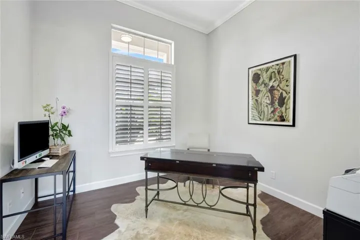 Office space with dark hardwood / wood-style flooring and crown molding