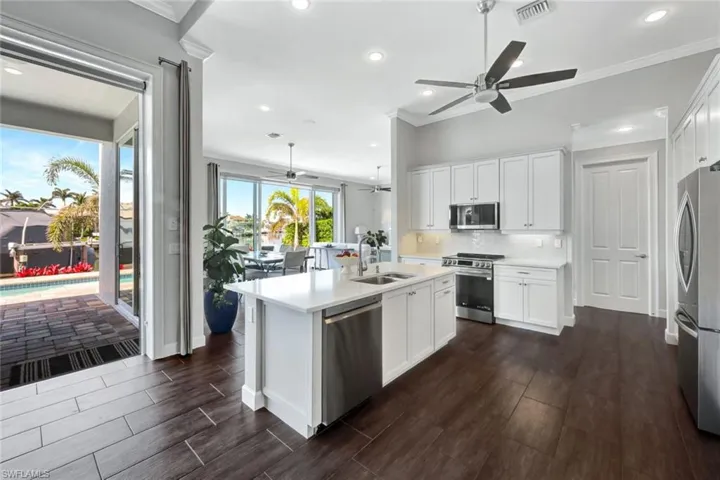 Kitchen featuring appliances with stainless steel finishes, a kitchen island with sink, sink, and white cabinets