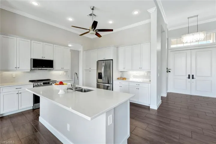 Kitchen featuring white cabinetry, sink, stainless steel appliances, and a center island with sink