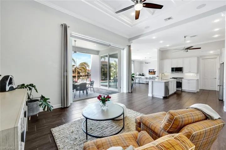 Living room featuring crown molding, ceiling fan, coffered ceiling, and sink