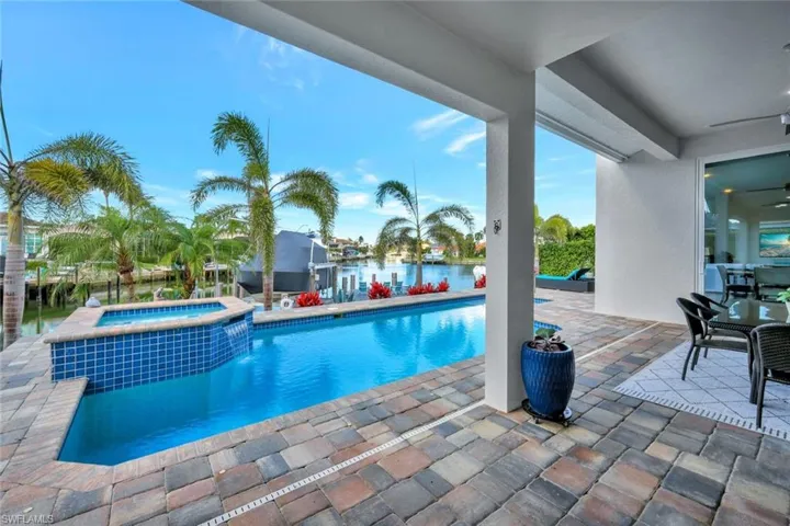 View of swimming pool with an in ground hot tub, a water view, and a patio