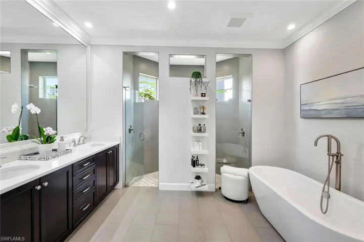 Bathroom with crown molding, plenty of natural light, independent shower and bath, and vanity
