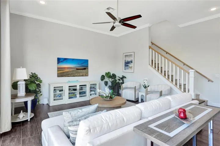 Living room with ornamental molding, dark hardwood / wood-style flooring, and ceiling fan