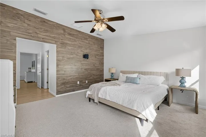 Carpeted bedroom featuring wooden walls, an accent wall, and a ceiling fan