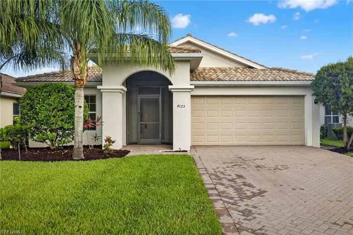 Mediterranean / spanish-style home featuring a tile roof, stucco siding, decorative driveway, an attached garage, and a front lawn