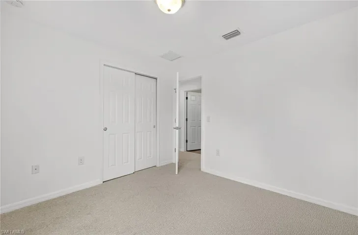 Unfurnished bedroom featuring light carpet and a closet