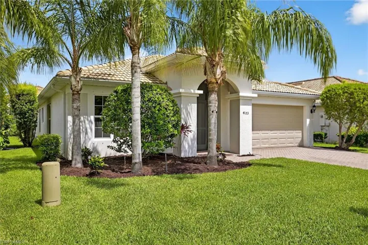 View of front of property featuring stucco siding, a garage, decorative driveway, a front yard, and a tiled roof