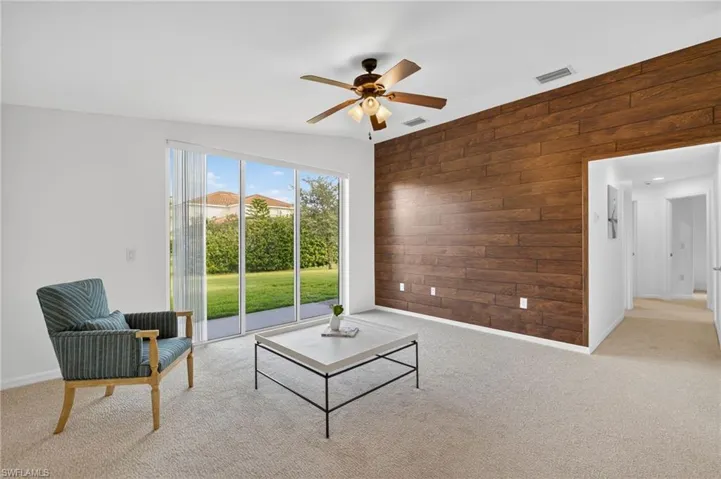Carpeted living area with wooden walls and a ceiling fan
