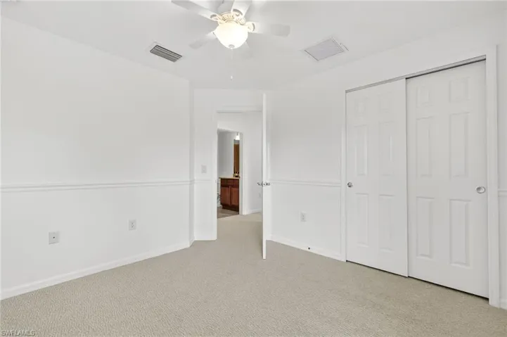 Unfurnished bedroom with light colored carpet, a closet, and ceiling fan