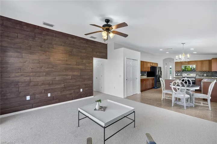 Living area featuring wood walls, a ceiling fan, arched walkways, a chandelier, and recessed lighting