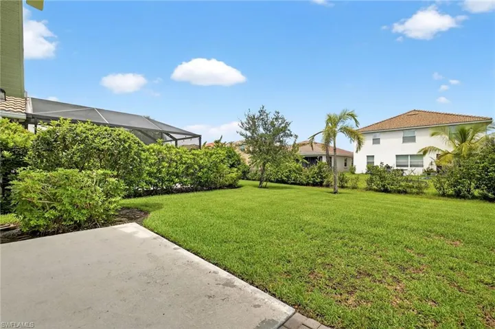 View of grassy yard featuring a patio area and a lanai