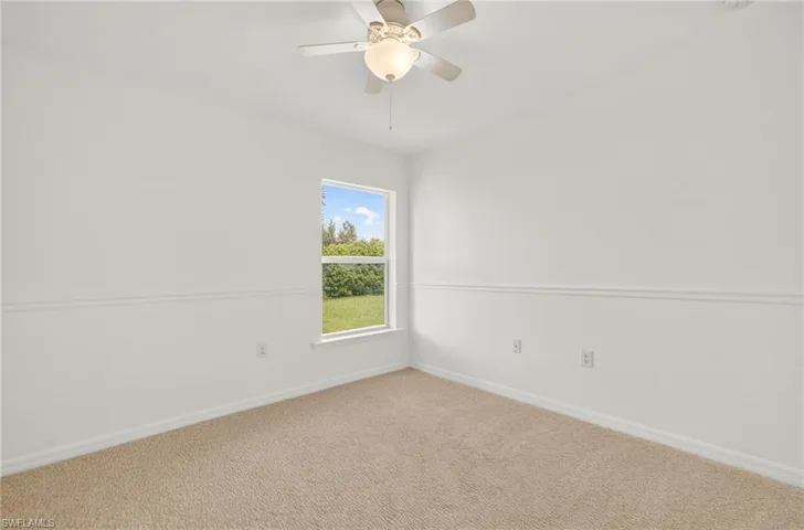 Carpeted spare room featuring baseboards and ceiling fan