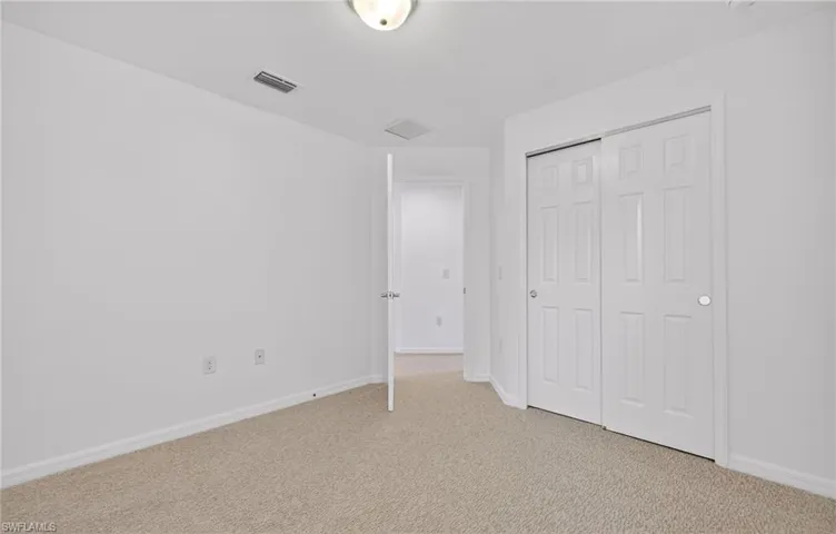 Unfurnished bedroom featuring light carpet and a closet