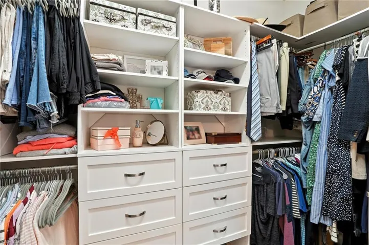 Custom closet system featuring multiple hanging rods, built-in shelving, and drawers with polished chrome hardware